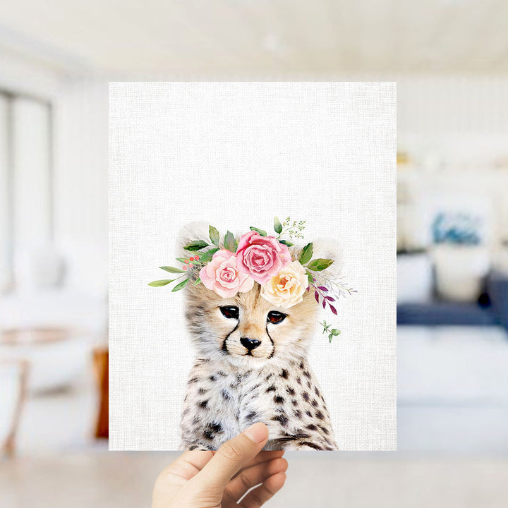 A hand is holding up a framed print of a cheetah wearing a floral crown.