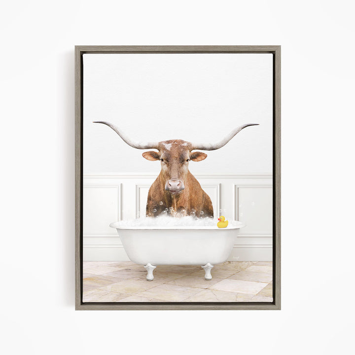 A bull with long horns is sitting in a white bathtub, with a rubber duck floating in the water.