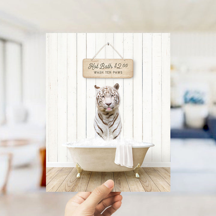 A hand holding a framed image of a white tiger sitting in a bathtub filled with water, with a sign above it that reads "Hot Bath $2.00 WASH YOUR Paws".