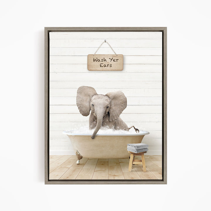 A gray elephant is sitting in a bathtub filled with water, with a wooden sign above it that says "Wash Your Ears".