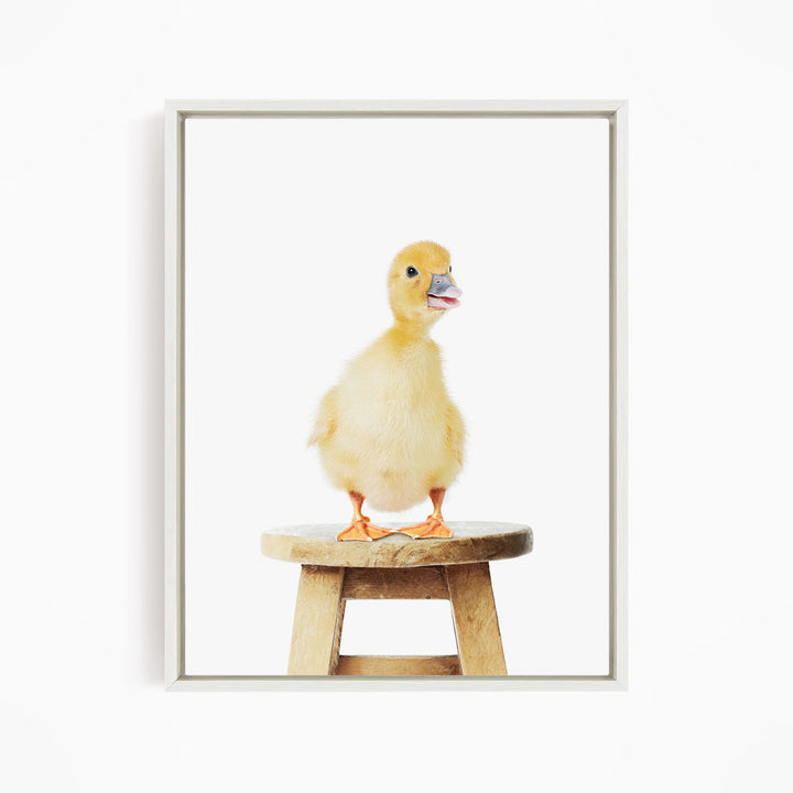 A small yellow duck standing on a wooden stool.