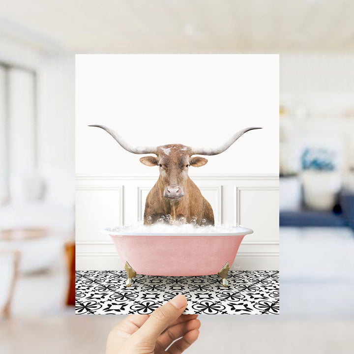 A brown bull with long horns is sitting in a pink bathtub filled with bubbles, creating a whimsical and playful scene.