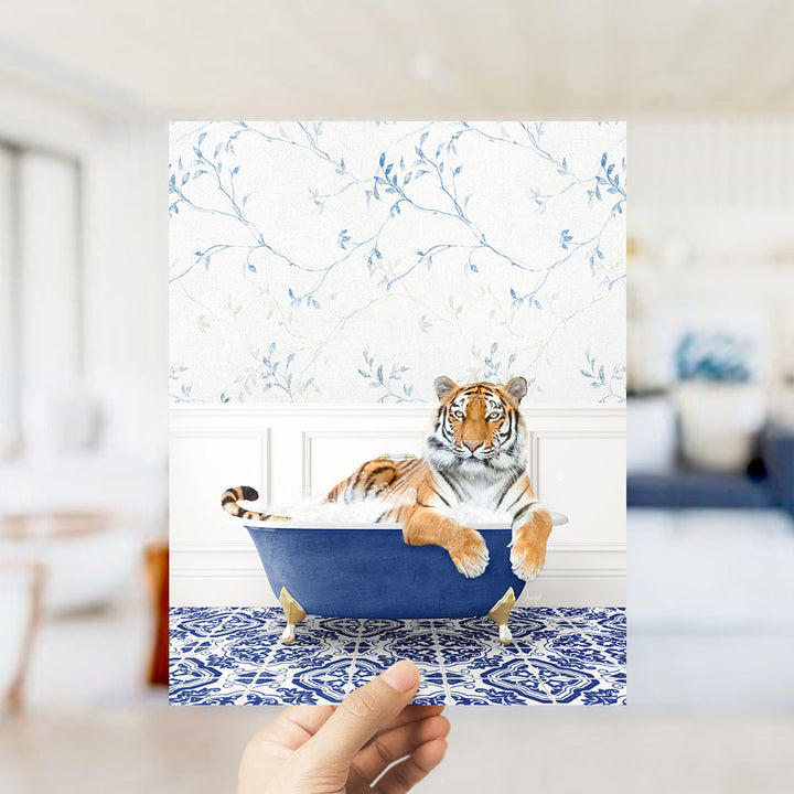A tiger is sitting in a blue bathtub, surrounded by a patterned blue and white rug, in a room with a floral wallpaper.