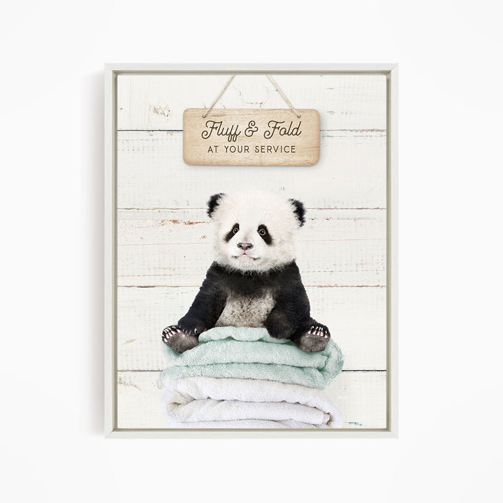A cute panda bear sitting on a stack of folded towels, with a wooden sign above that says "Fuffy & Fold at your service".