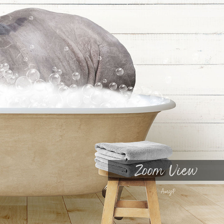 A large bathtub filled with bubbles, with a gray elephant partially submerged in the water. A wooden stool is placed next to the tub, and there are towels nearby.