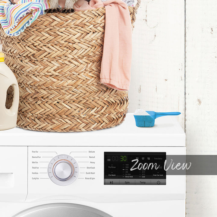 A laundry basket filled with clothes and a bottle of detergent sits next to a washing machine with a digital display.