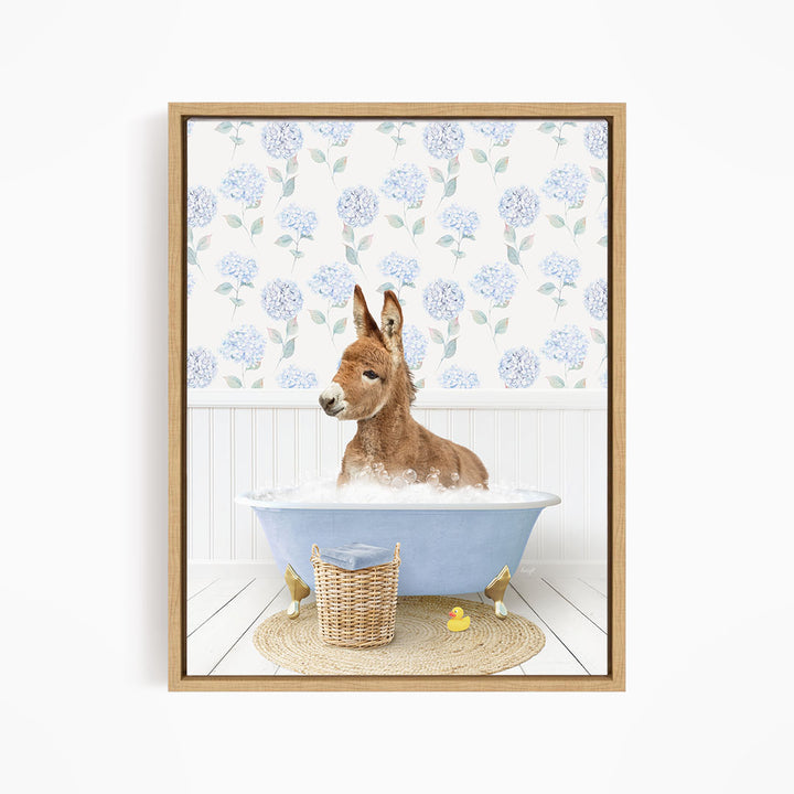 A donkey is sitting in a blue bathtub filled with water, surrounded by a wicker basket and rubber ducks.