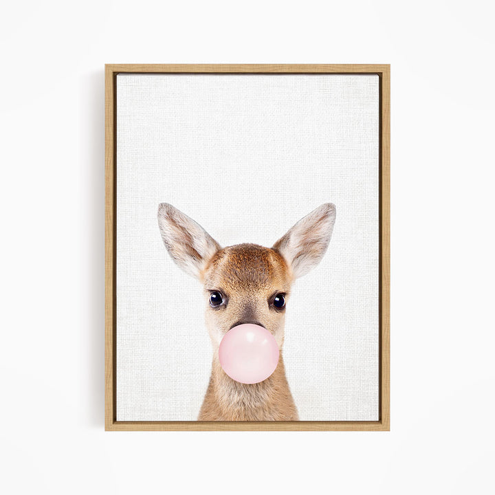 A deer with large ears blowing a pink bubblegum bubble.