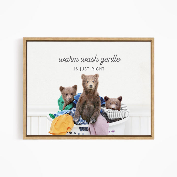 A framed image depicting three bears sitting in a laundry basket, with the text "Warm wash gentle is just right" written above them.