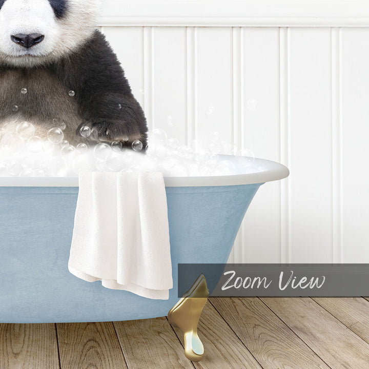 A panda bear sitting in a blue bathtub filled with bubbles, with a towel and a gold object nearby.