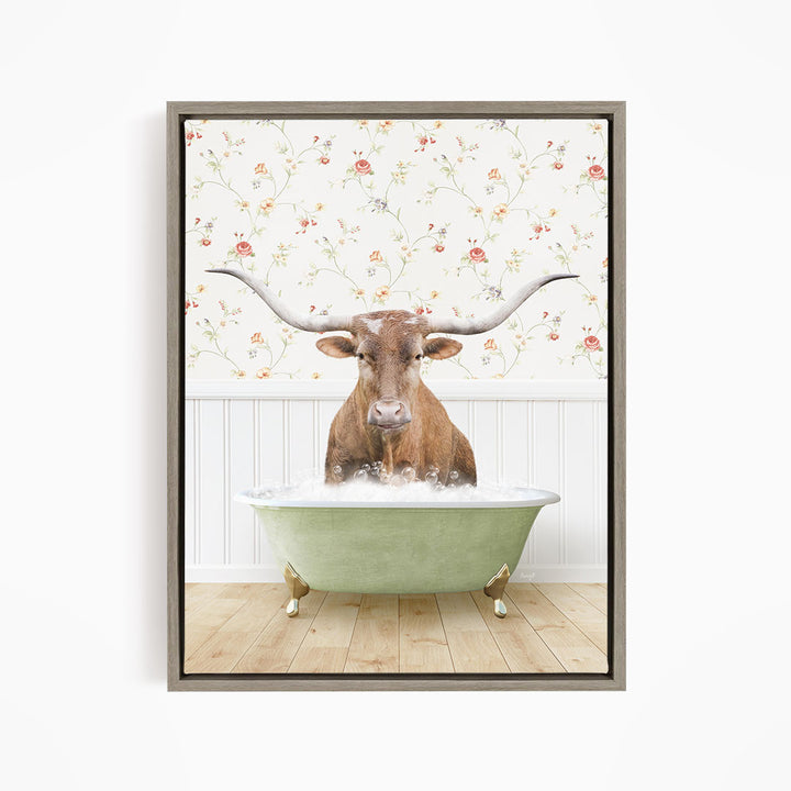 A brown steer with large horns is sitting in a green bathtub filled with water, surrounded by a floral wallpaper.