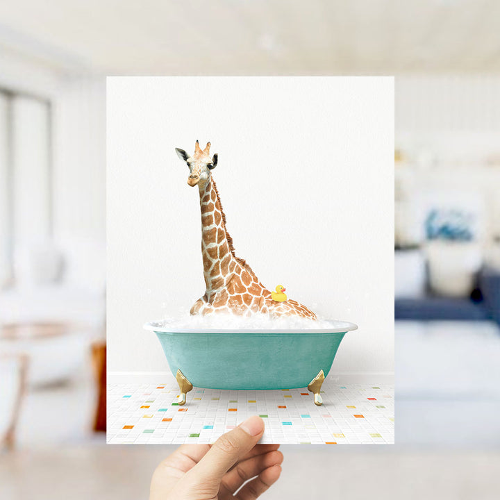 A giraffe sitting in a teal bathtub filled with bubbles, with a rubber duck floating in the water.