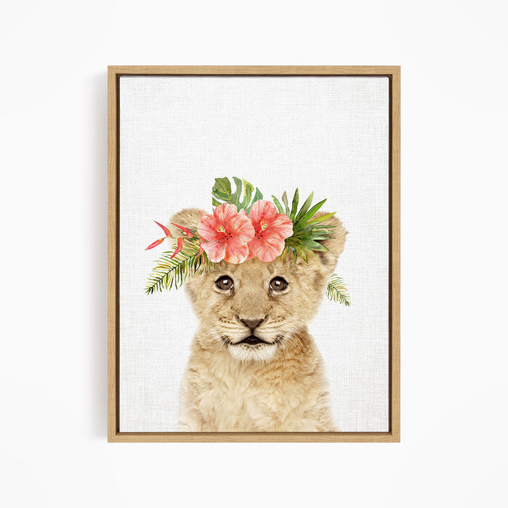 A young lion cub wearing a floral headpiece with pink and red flowers and green leaves.