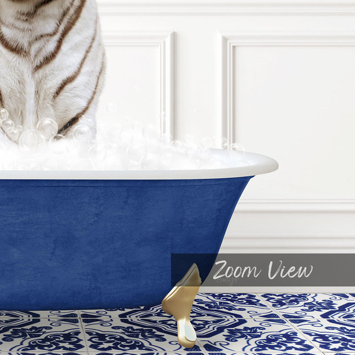 A white and brown striped cat standing in a blue bathtub filled with bubbles, with a gold bathtub stand visible.