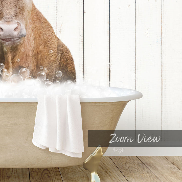 A brown cow is sitting in a bathtub filled with bubbles, with a towel draped over the side of the tub.