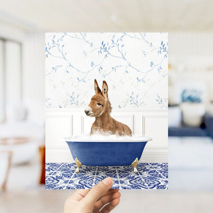 A donkey is sitting in a blue bathtub filled with bubbles, surrounded by a patterned tile floor and a floral wallpaper.
