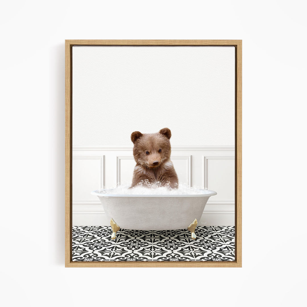 A brown bear sitting in a white bathtub filled with bubbles, looking directly at the camera.