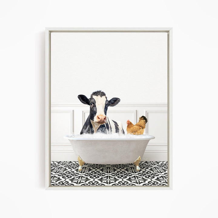 A black and white cow is sitting in a white bathtub, with a chicken standing nearby, in a white-framed picture.