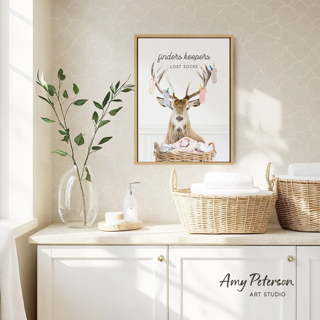 a framed poster of a deer with antlers, hanging on a wall above a white cabinet with baskets.