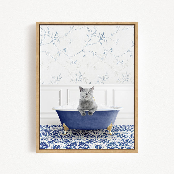 A gray cat sitting in a blue bathtub filled with bubbles, with a patterned tile floor and a floral wallpaper in the background.
