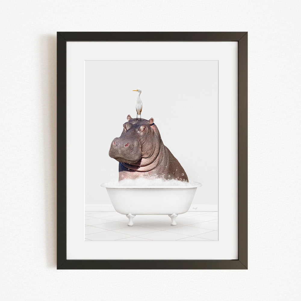 A framed image depicting a hippopotamus sitting in a bathtub, with a seagull perched on its head.