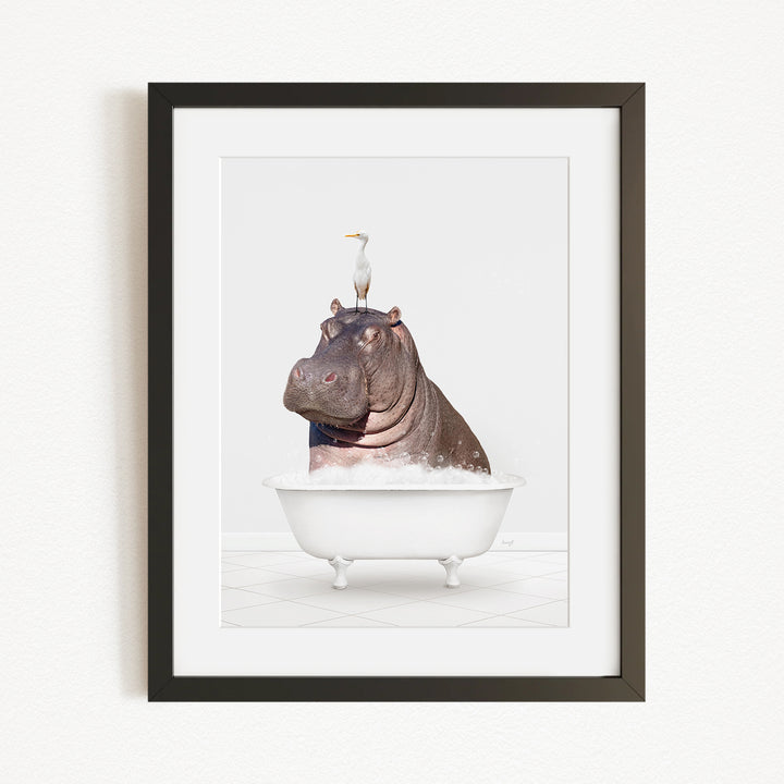 A framed image depicting a hippopotamus sitting in a bathtub, with a seagull perched on its head.