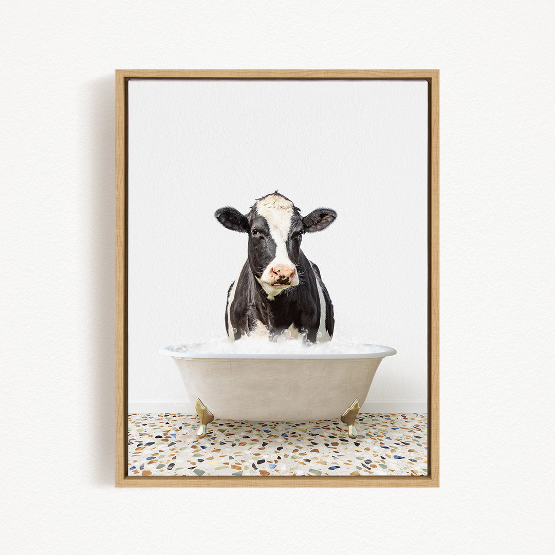 A black and white cow standing in a white bathtub filled with water, creating a whimsical and humorous scene.