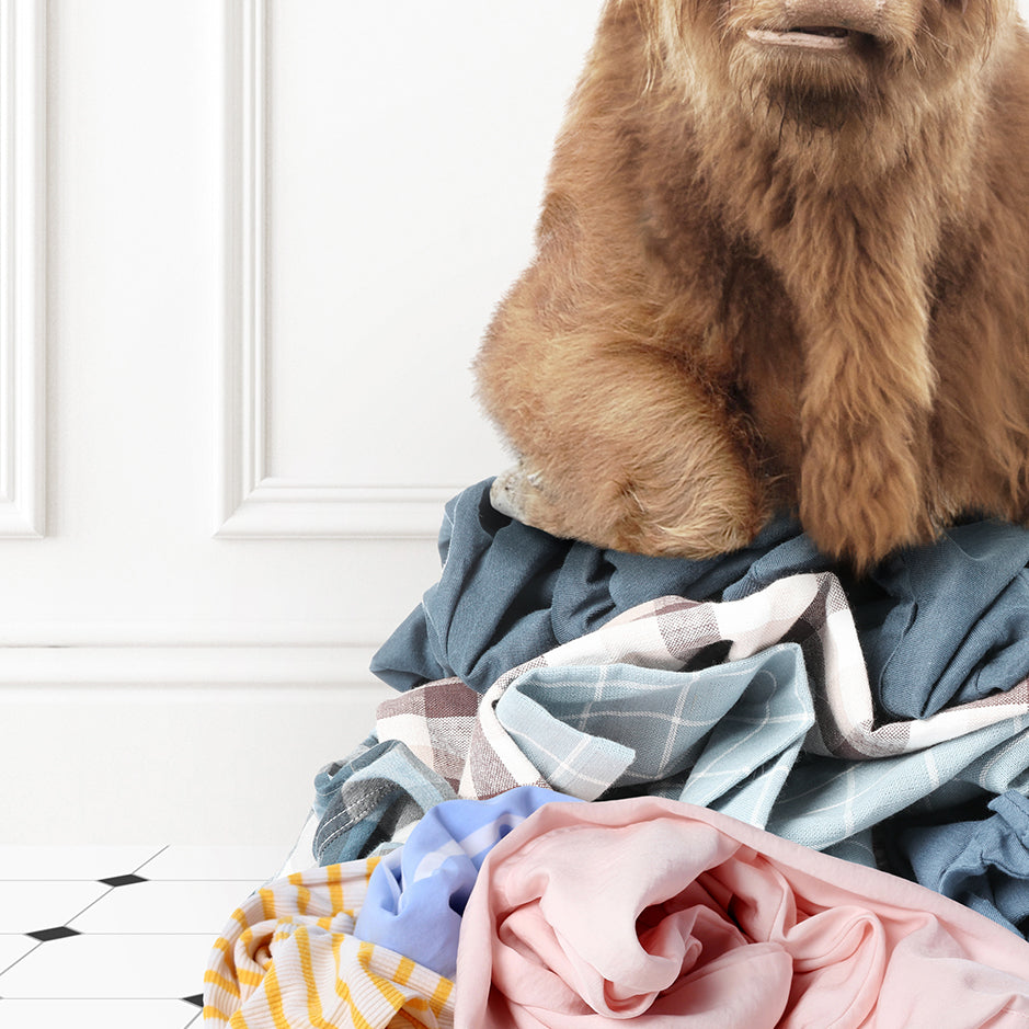 a stuffed bear sitting on top of a pile of clothes