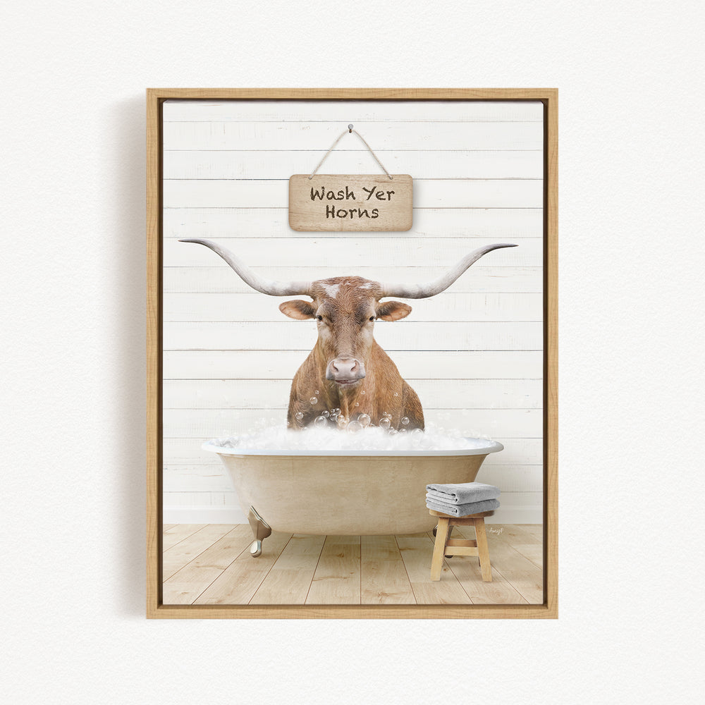 A framed image depicting a bull with large horns sitting in a bathtub, with a sign above that says "Wash Your Horns".