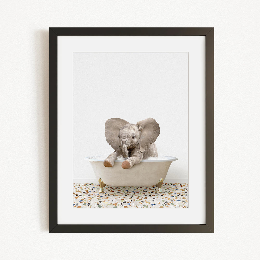 A baby elephant sitting in a bathtub, with its trunk raised and ears spread out, creating a playful and whimsical scene.