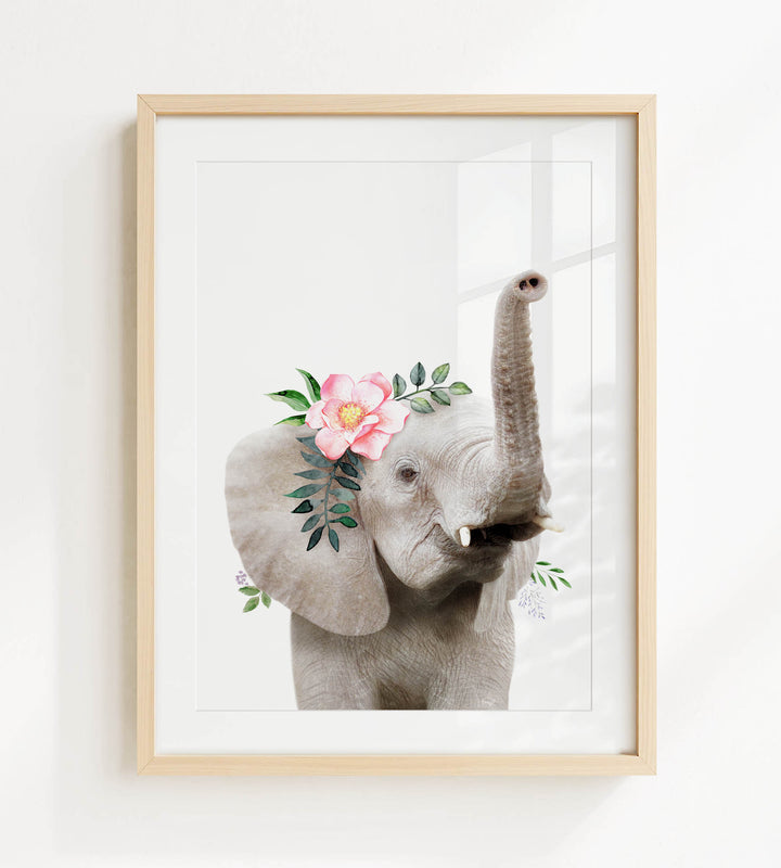 A framed print of an elephant with a pink flower on its head and green leaves around its trunk.