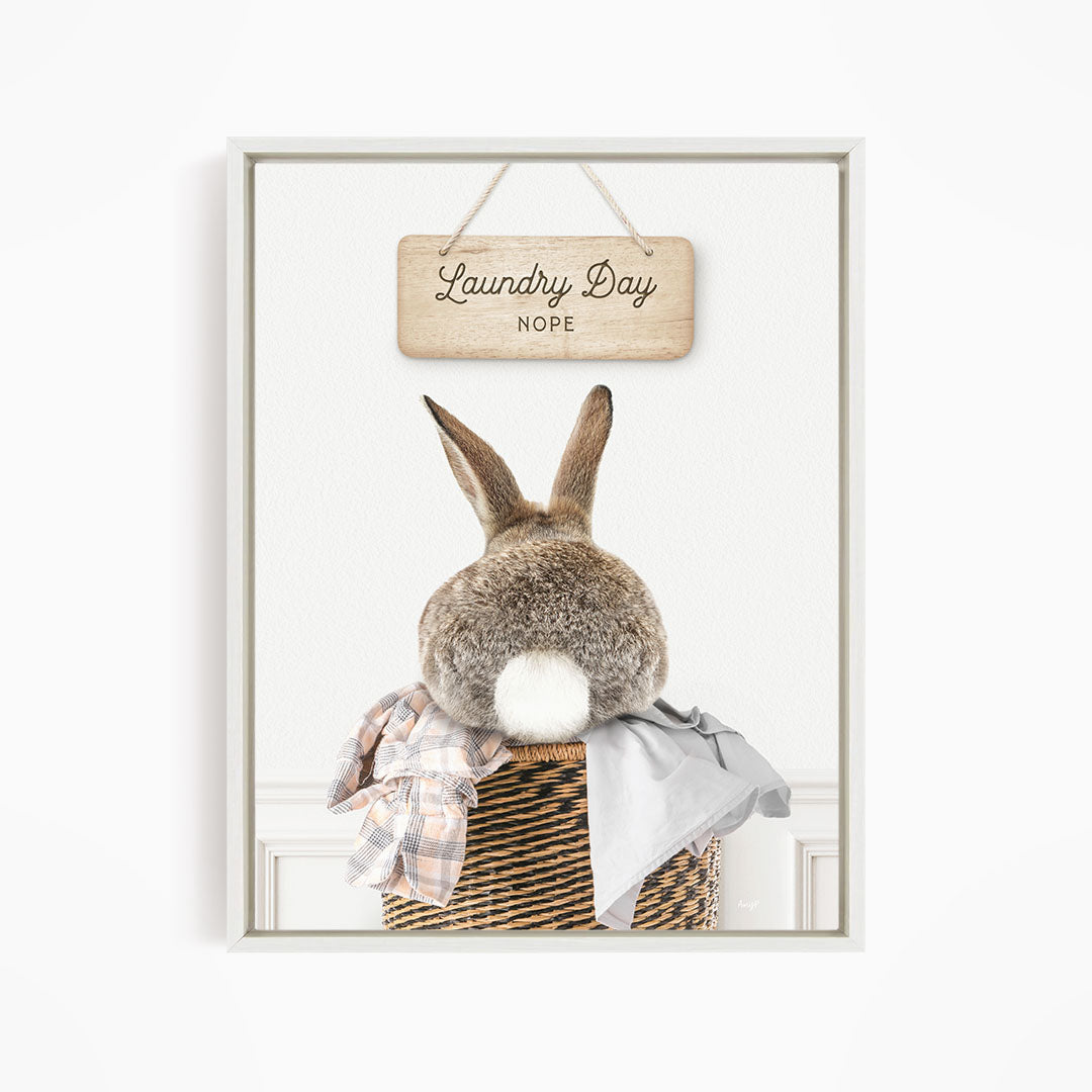 A wooden sign with the text "Laundry Day NOPE" hangs above a basket containing a plaid blanket and a gray shirt.