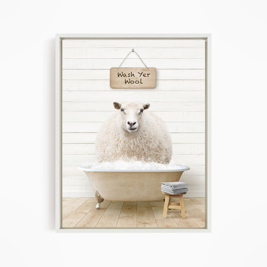 A fluffy white sheep is sitting in a bathtub filled with bubbles, with a sign above it that says "Wash Yer Wool".