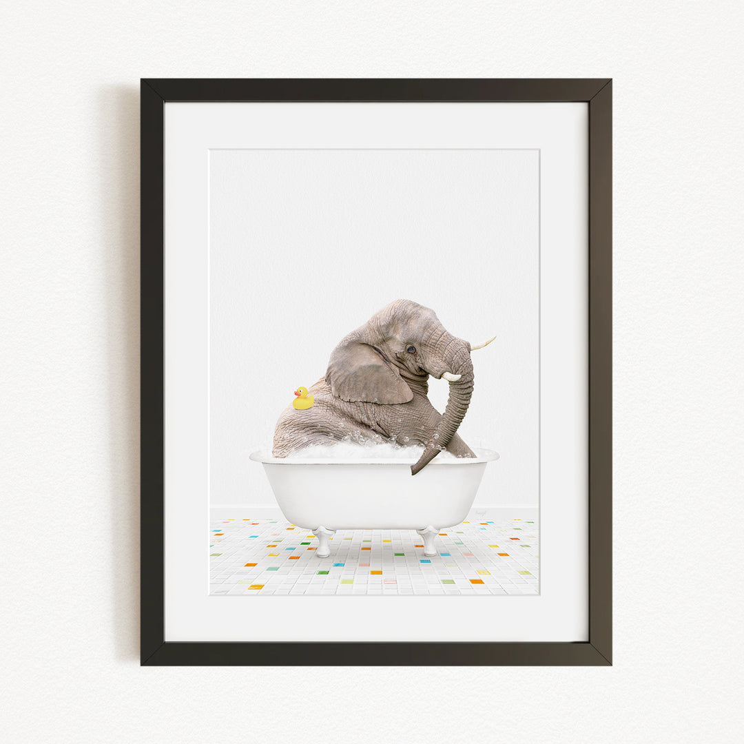 A gray elephant is sitting in a white bathtub, with a yellow rubber duck floating next to it.