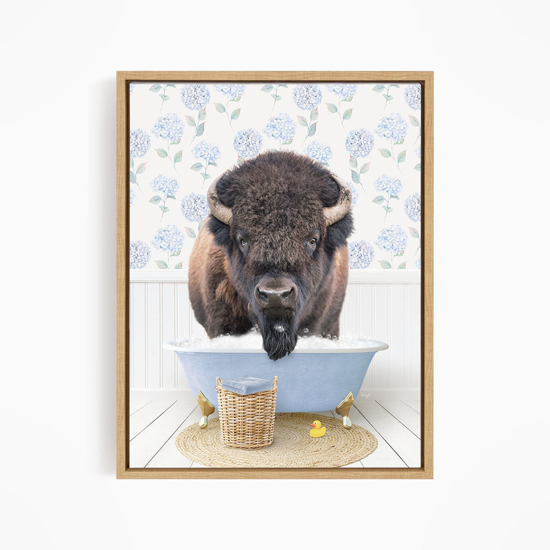 A buffalo is sitting in a blue bathtub filled with water, surrounded by rubber ducks and a basket.