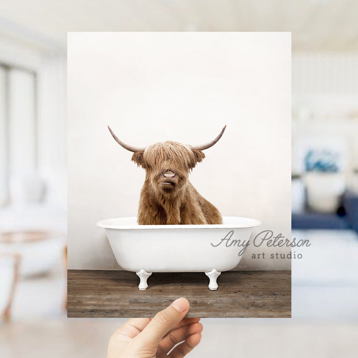 a hand holding up a photo of a cow in a bathtub