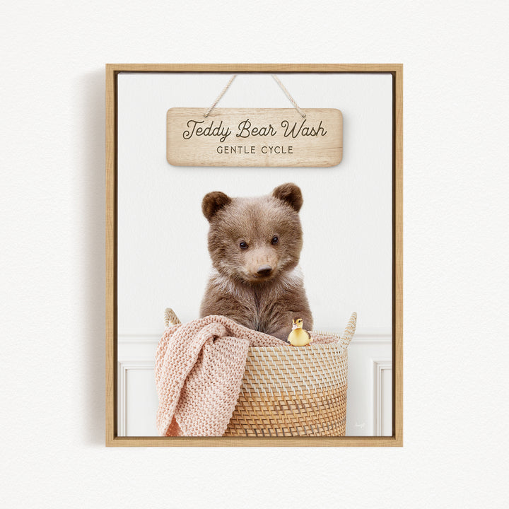 A wooden sign with the text "Teddy Bear Wash Gentle Cycle" hangs above a woven basket containing a teddy bear and a small yellow duck.