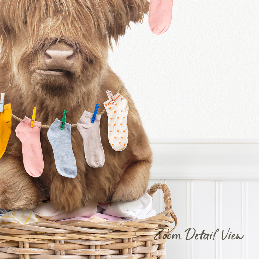 A brown cow is sitting in a wicker basket, holding a clothesline with colorful socks hanging on it.