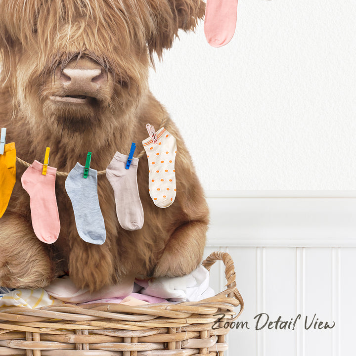 A brown cow is sitting in a wicker basket, holding a clothesline with colorful socks hanging on it.