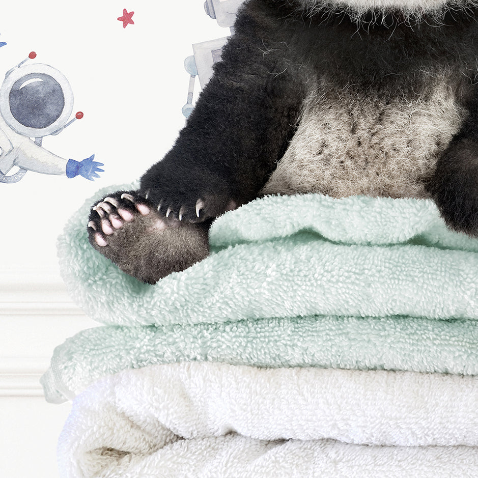 a panda bear sitting on top of a pile of towels