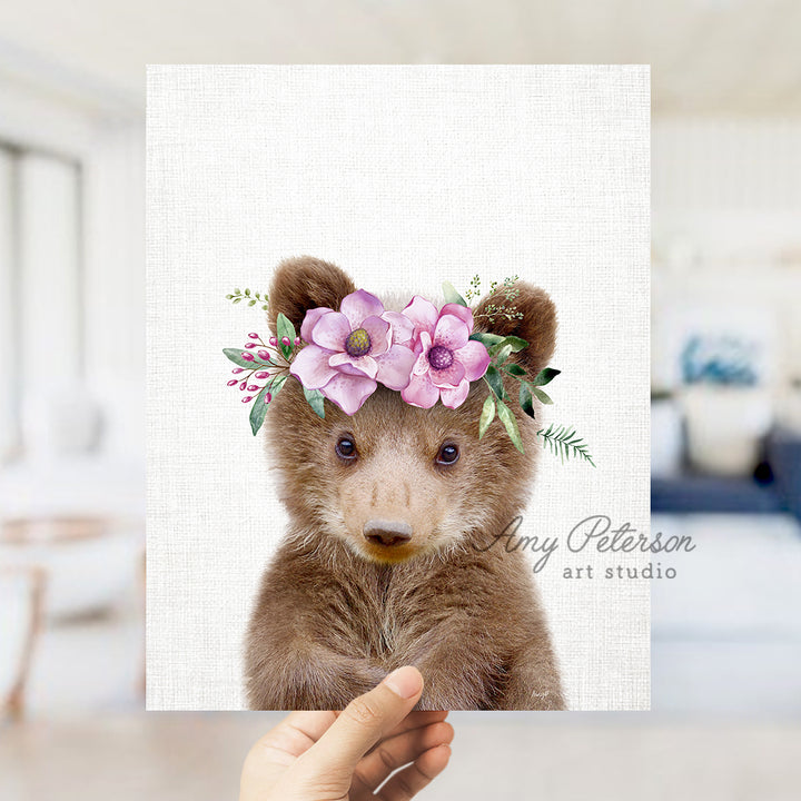 a hand holding a card with a picture of a teddy bear wearing a flower crown