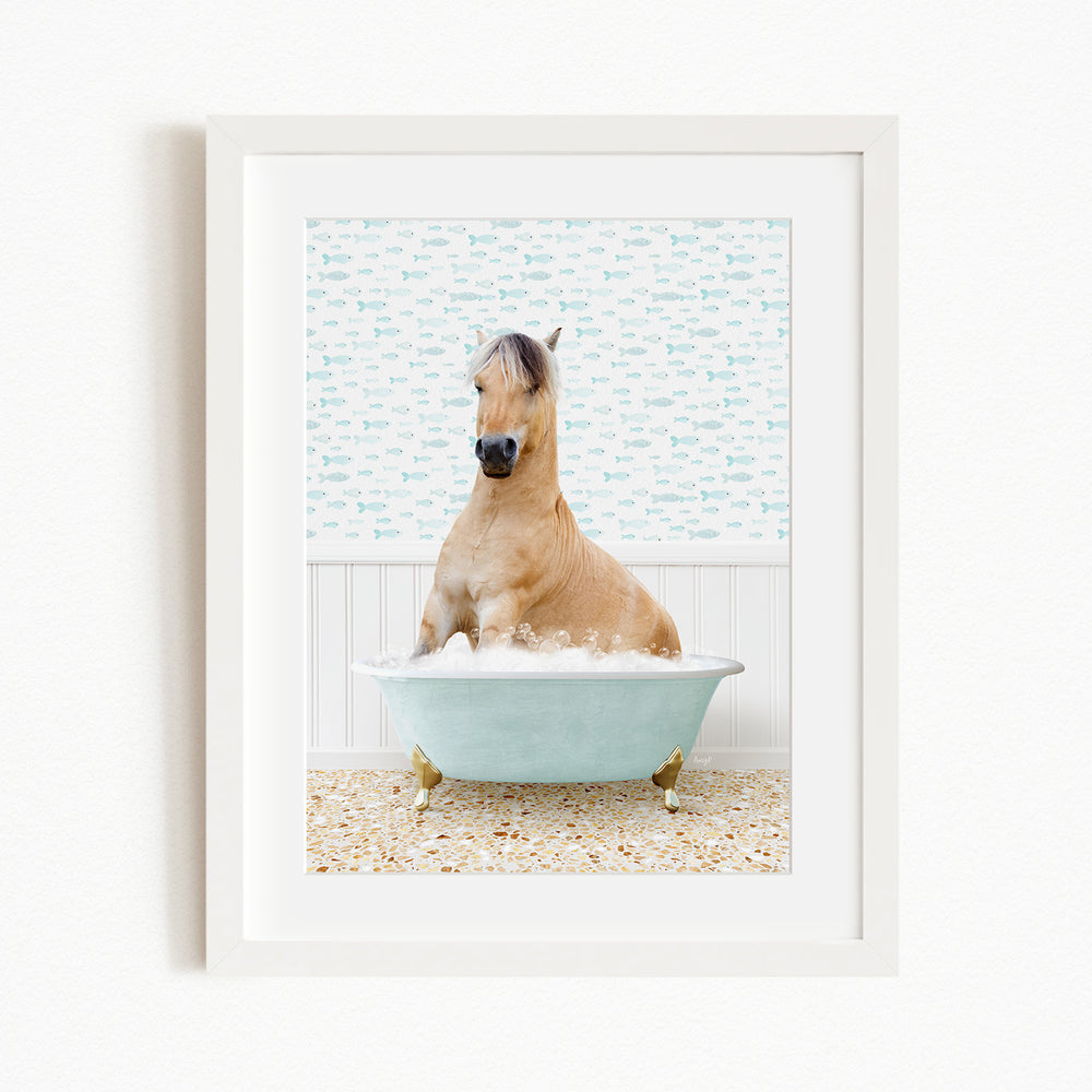 A light brown horse is sitting in a blue bathtub filled with water, surrounded by a patterned tile floor.