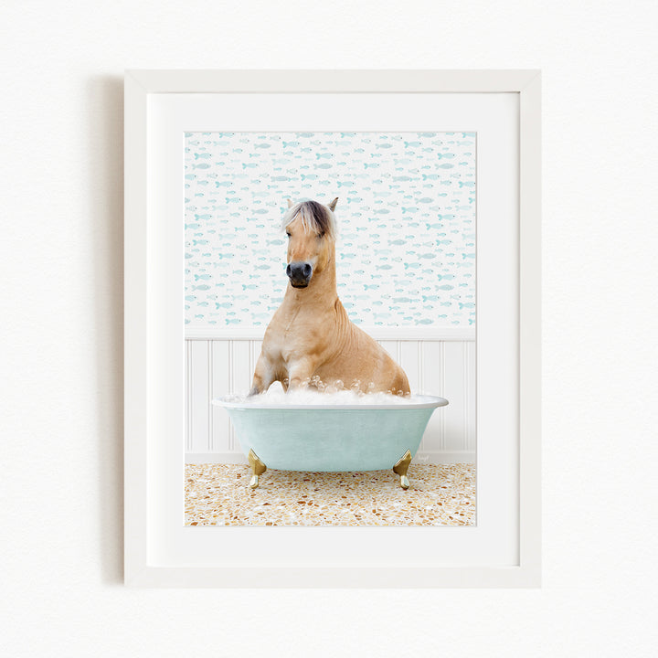 A light brown horse is sitting in a blue bathtub filled with water, surrounded by a patterned tile floor.