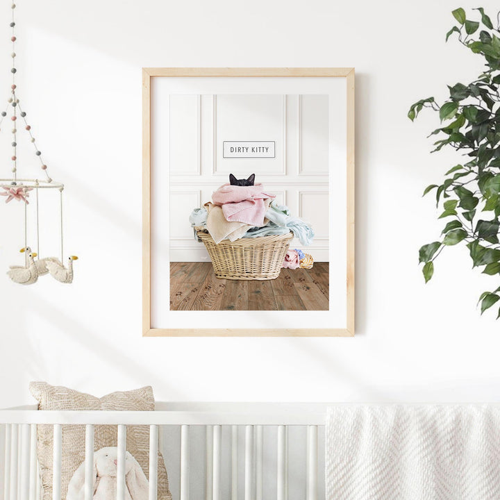 A framed image of a cat sitting in a basket of laundry, with the text "Dirty Kitty" on the frame.