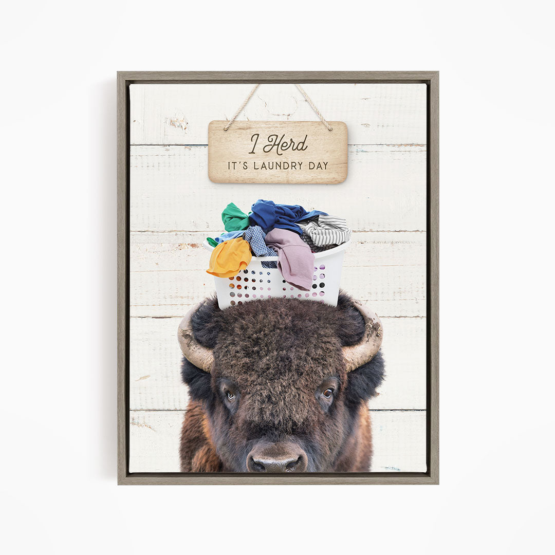 A buffalo with a basket of laundry on its head, accompanied by a wooden sign that says "It's laundry day".