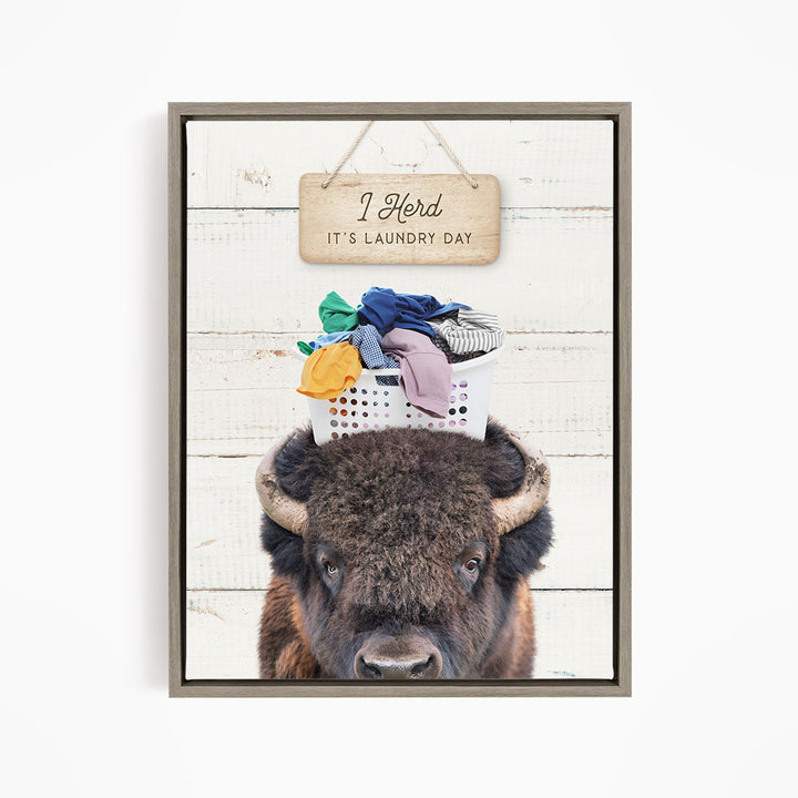 A buffalo with a basket of laundry on its head, accompanied by a wooden sign that says "It's laundry day".