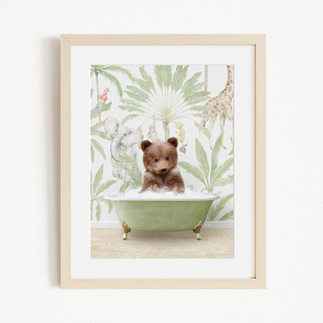 A framed image depicting a small brown bear sitting in a green bathtub, surrounded by a tropical jungle wallpaper.