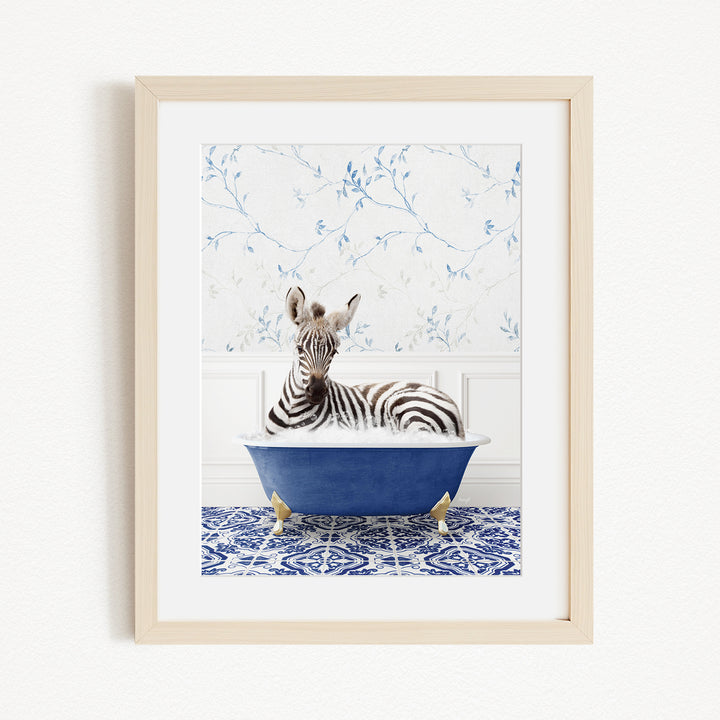 A zebra is sitting in a blue bathtub, surrounded by a blue and white patterned rug and a white wall with blue floral wallpaper.