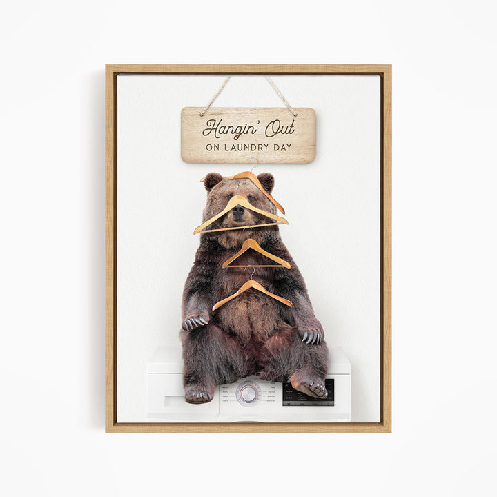 A framed image of a bear sitting on a washing machine, with a sign above it that says "Hangin' Out on laundry day".