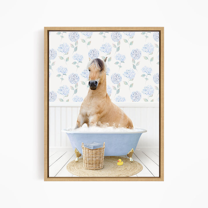 A light brown horse is sitting in a blue bathtub filled with water, surrounded by a wicker basket and rubber duckies.